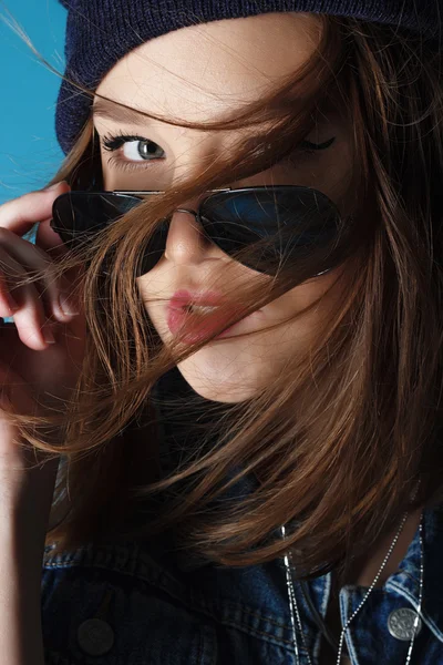 Стильная модная рок-девушка в джинсовой шляпе и солнцезащитных очках в студии — стоковое фото