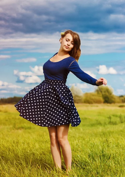 Stylish hipster girl in the blue dress with the flowers in the field — Stock Photo, Image