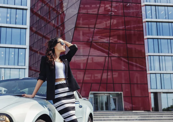 Beautiful business woman on the background of the modern office near the sport car