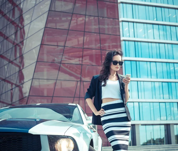 Hermosa mujer de negocios en el fondo de la oficina moderna cerca del coche deportivo —  Fotos de Stock