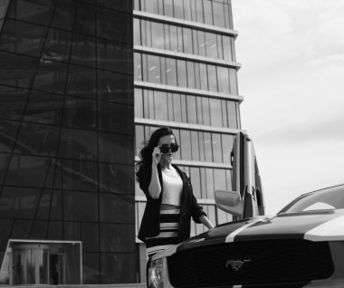 Güzel iş kadını modern ofis yakınındaki spor araba arka plan üzerinde