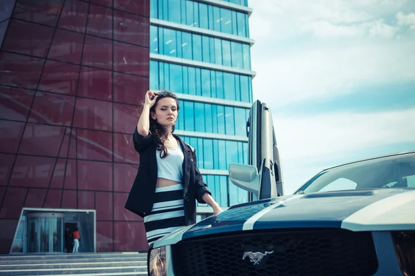 Красивая деловая женщина на фоне современного офиса рядом со спорткаром — стоковое фото