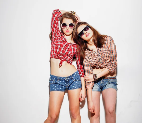 Közelről divat-életmód portréja két fiatal hipster lányok legjobb barátja, fényes alkotó és divatos ruhákat visel, hogy vicces arcok és szürke idő. Városi háttér. — Stock Fotó