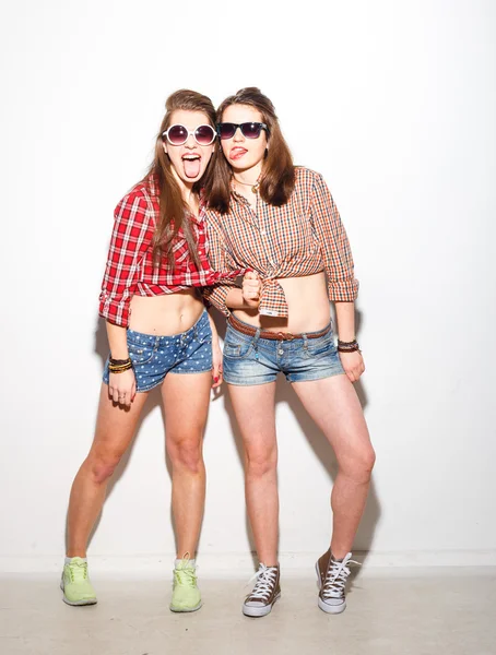 Close-up mode levensstijl portret van twee jonge hipster meisjes beste vrienden, lichte make-up en trendy kleding dragen, het maken van grappige gezichten en grijze tijd hebben. Stedelijke achtergrond. — Stockfoto