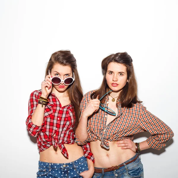 Gros plan mode style de vie portrait de deux jeunes filles hipster meilleurs amis, portant maquillage lumineux et vêtements à la mode, faire des grimaces drôles et ont le temps gris. Contexte urbain . — Photo