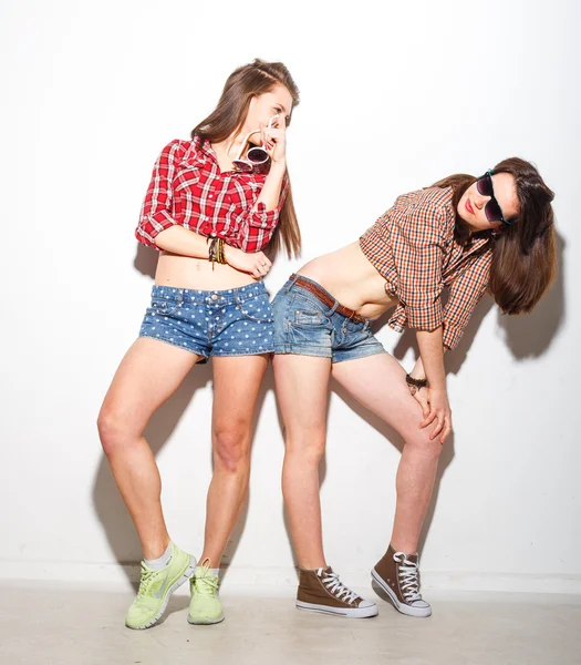 Primer plano estilo de vida de la moda retrato de dos chicas hipster jóvenes mejores amigos, el uso de maquillaje brillante y ropa de moda, haciendo caras divertidas y tienen tiempo gris. Fondo urbano . —  Fotos de Stock