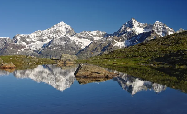 Lago alpino com reflexo de montanhas na água — Fotografia de Stock