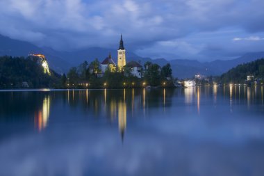 Suya yansıyan alacakaranlıkta Bled Gölü ve hac Kilisesi