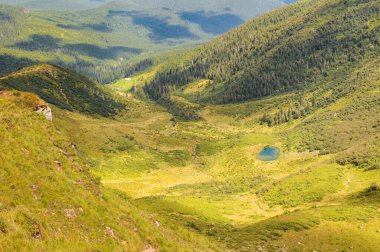 Güneşli yaz gününde Küçük Apshynets buzul gölü ve Svydovets dağ sırasının manzarası. Ukrayna 'nın en popüler tatil beldelerinden birinin inanılmaz yaz manzarası.