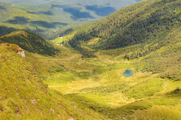 Güneşli yaz gününde Küçük Apshynets buzul gölü ve Svydovets dağ sırasının manzarası. Ukrayna 'nın en popüler tatil beldelerinden birinin inanılmaz yaz manzarası.
