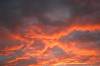 Batan güneşten gelen parlak turuncu ve kırmızı ışığı yakalayan dramatik bulutlar çarpıcı bir soyut doğal zemin ve canlı, sıcak bir atmosfer görüntüsü yaratıyor.