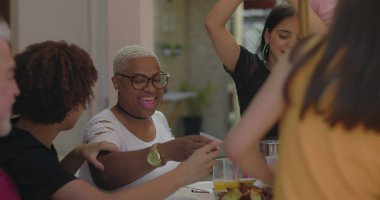 Bir grup arkadaş gülerek ve dışarıda eğlenerek, güneşin altında coşkulu bir şekilde toplanan, bağın, kutlamanın ve sevincin altını çizerek