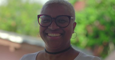 Gülümseyen kıvırcık saçlı, siyah gömlekli, kendine güveni ve neşe saçan, yeşil, sıcak ve dost canlısı, güler yüzlü genç İspanyol çocuk.