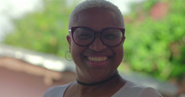 Gülümseyen kıvırcık saçlı, siyah gömlekli, kendine güveni ve neşe saçan, yeşil, sıcak ve dost canlısı, güler yüzlü genç İspanyol çocuk.