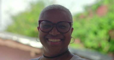 Gülümseyen kıvırcık saçlı, siyah gömlekli, kendine güveni ve neşe saçan, yeşil, sıcak ve dost canlısı, güler yüzlü genç İspanyol çocuk.