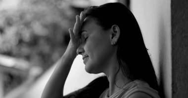 Duvara yaslanmış bir kadın, alnına yaslanmış, pişmanlık ve duygusal ifade, siyah beyaz yakın plan, derin yansıma ve pişmanlık anı