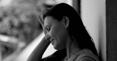 Duvara yaslanmış bir kadın, alnına yaslanmış, pişmanlık ve duygusal ifade, siyah beyaz yakın plan, derin yansıma ve pişmanlık anı