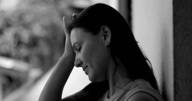 Duvara yaslanmış bir kadın, alnına yaslanmış, pişmanlık ve duygusal ifade, siyah beyaz yakın plan, derin yansıma ve pişmanlık anı