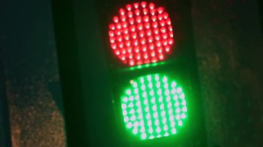 Şehir caddesinde gece kırmızıdan yeşile dönen trafik ışığı, sinyal geçişi olarak parlayan LED ampuller, gitmek ve şehir trafik akış kontrolünü sembolize eden trafik ışığı