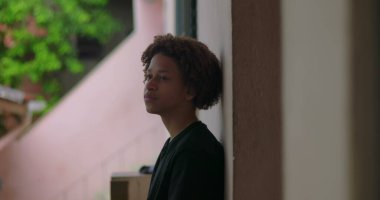 Afrika kökenli, kıvırcık saçlı, derin düşüncelere dalmış, açık havada yansıyan, barışçıl bir ifade, yukarıya bakan, içe dönük bir çocuk.