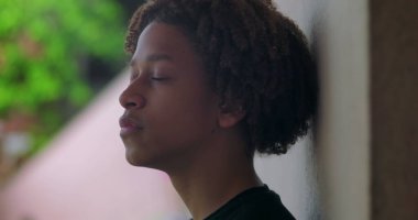 Latin kökenli, gözleri kapalı bir çocuk, dış mekanı yansıtıyor, sakin ifade, meditasyon, huzurlu an, iç huzur, maneviyat, düşünceli duraksama