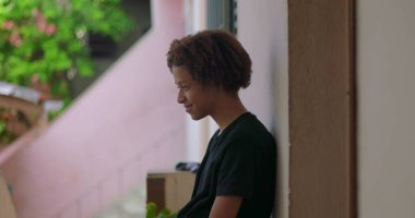 Pozitif enerjiyle gülümseyen, duvara yaslanmış, Afrika kökenli, neşeli an, duygusal rahatlama, açık hava manzarası, yakın çekim