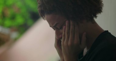 Duygusal sıkıntı içindeki genç bir çocuk, elleri yüzünü kapatıyor, ağlıyor, duvara yaslanıyor, Afrika kökenli, açık hava manzaralı, yakın plan.