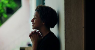 Afrika kökenli, kıvırcık saçlı, gözleri kapalı, açık havada dua eden elleri birbirine kenetlenmiş, derin ruhsal yansıması olan, huzurlu bir çocuk.