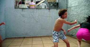 Avluda kovalamaca oynayan çocuklar, birbirini kovalayan kaygısız gülüşler, enerjik çocukluk anları, aile bağları, açık havada neşeli zaman geçirme, basit eğlence.