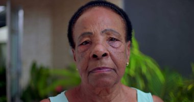 Ciddi ve sakin bir ifadeye sahip yaşlı Afrikalı Amerikalı kadının yakın plan portresi, açık hava bahçesi geçmişi, bilgelik anlayışı, güç ve son sınıf öğrencilerinin varlığı.