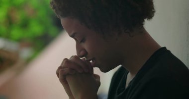 Duygusal sıkıntı içindeki genç bir çocuk, elleri yüzünü kapatıyor, ağlıyor, duvara yaslanıyor, Afrika kökenli, açık hava manzaralı, yakın plan.