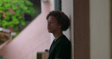 Afrika kökenli, kıvırcık saçlı, barışçıl gülüşlü, açık havada yansıyan, sakin bir ifade, ruhani bir an, sakin bir düşünce, düşünceli bir duraksama.