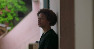 Afrika kökenli, kıvırcık saçlı, barışçıl gülüşlü, açık havada yansıyan, sakin bir ifade, ruhani bir an, sakin bir düşünce, düşünceli bir duraksama.