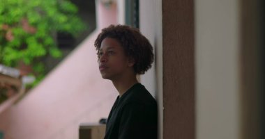 Afrika kökenli, kıvırcık saçlı, derin düşüncelere dalmış, açık havada yansıyan, barışçıl bir ifade, yukarıya bakan, içe dönük bir çocuk.