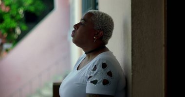 Latin kökenli Afrikalı bir kadın, elini kaldırmış ve el kol hareketi yapıyor, derin duygular gösteriyor, zor zamanlarda eziliyor ve pişmanlık duyuyor, doğal arka plan