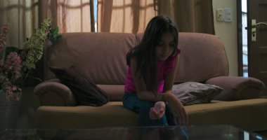 Genç bir kız loş bir odada tek başına oturuyor, kafası eğik, izolasyon, duygusal mücadele ve sakin bir ev ortamında çocukluk bunalımı tasvir ediyor.