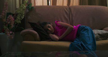 Kapalı bir koltukta uzanan genç kız, yalnızlığı ve duygusal uzaklığı somutlaştırıyor, çocukluk yalnızlığı, depresyon, zihinsel sağlık sorunları ve iç gözlem konularını yansıtıyor.