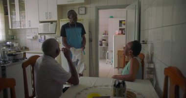 Afrika kökenli bir aile mutfakta toplandı. Yaşlı bir çift masada otururken bir adam yakınlarda, rahat ve samimi bir aile bağı ve günlük yaşam sürüyor.