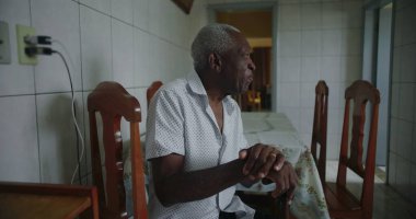 Yaşlı Afro-Amerikalı adam mutfakta oturmuş içten bir şekilde gülüyor ve gülüyordu. Huzurlu ve samimi bir evde mutluluk ve neşe ifade ediyordu.