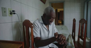 Yaşlı Afro-Amerikalı adam mutfakta oturmuş içten bir şekilde gülüyor ve gülüyordu. Huzurlu ve samimi bir evde mutluluk ve neşe ifade ediyordu.