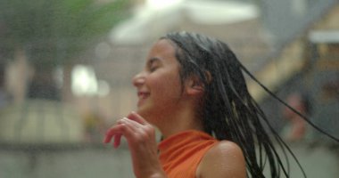 Suyun altında neşeyle oynayan çocuk, dinamik hareketlerle uçan saçlar, kaygısız bir heyecan, gençlik enerjisi ve serinletici yaz eğlencesi.