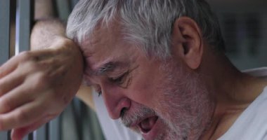 Yaşlı adam parmaklıklara yaslanıyor, kafası derin umutsuzluğa düşmüş, duygusal acı tarafından tüketilmiş, acının dramatik bir temsili, umutsuzluk, ve yaşlanma mücadelesi