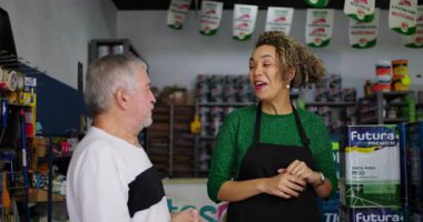 Gülümseyen esnaf, yaşlı bir müşteriyle bir hırdavatçıda keyifli anlar yaşıyor. Mükemmel müşteri hizmetleri ve kişisel bağlantılarını sergiliyor.