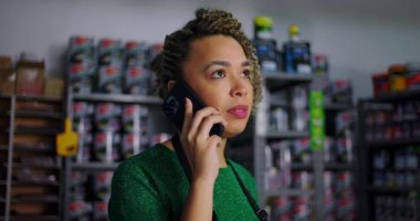 Hırdavatçıdaki bir telefon görüşmesine odaklanmış, arka planda raflar dolusu boya ve malzeme, müşteri soruşturmalarını yönetmek ve birden fazla işi profesyonelce yapmak