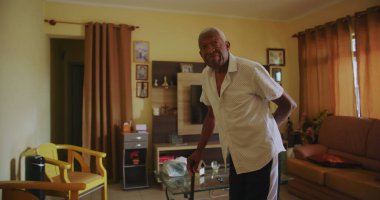 Bastonlu yaşlı Afro-Amerikalı bir adam rahat bir oturma odasında dikkatlice yürüyor. Huzurlu bir ev ortamında kararlılık ve bağımsızlık gösteriyor.