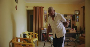 Bastonlu yaşlı Afro-Amerikalı bir adam rahat bir oturma odasında dikkatlice yürüyor. Huzurlu bir ev ortamında kararlılık ve bağımsızlık gösteriyor.