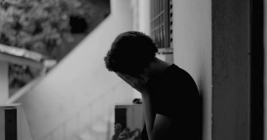 Kafası keder ve umutsuzlukla eğilmiş, çocukluk yalnızlığı ve duygusal hassasiyetini temsil eden bir duvar başında tek başına duran Afrikalı Amerikalı çocuk.