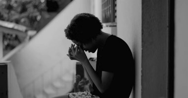 Kafası keder ve umutsuzlukla eğilmiş, çocukluk yalnızlığı ve duygusal hassasiyetini temsil eden bir duvar başında tek başına duran Afrikalı Amerikalı çocuk.