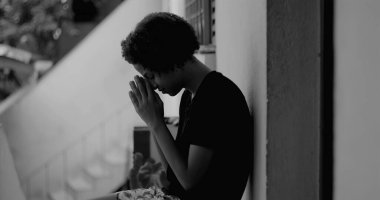 Kafası keder ve umutsuzlukla eğilmiş, çocukluk yalnızlığı ve duygusal hassasiyetini temsil eden bir duvar başında tek başına duran Afrikalı Amerikalı çocuk.