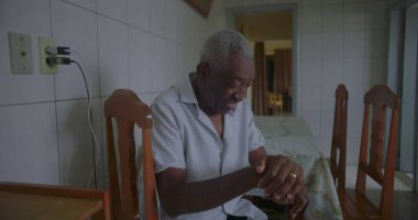 Bastonuyla mutfakta yürüyen, neşeyle gülümseyen, dengeyi, gücü ve mutluluğu sakin bir anda gösteren yaşlı Afrikalı Amerikalı adam.